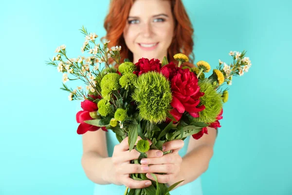 Happy young woman holding beautiful flowers on color background — Stock Photo, Image