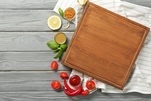Placa de madeira, diferentes molhos e legumes na mesa — Fotografia de Stock