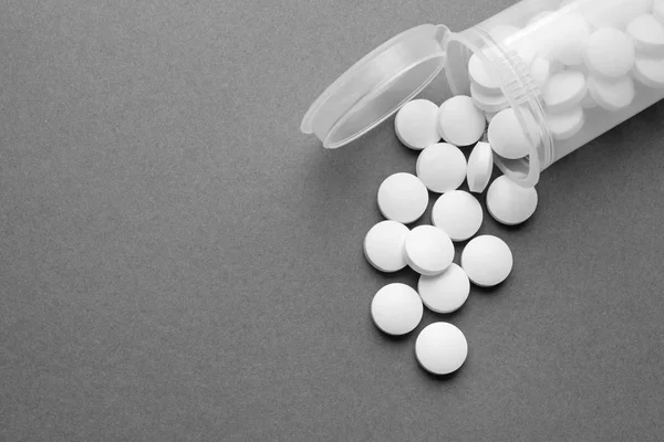 Concetto sanitario. Pillole e barattolo su sfondo grigio — Foto Stock