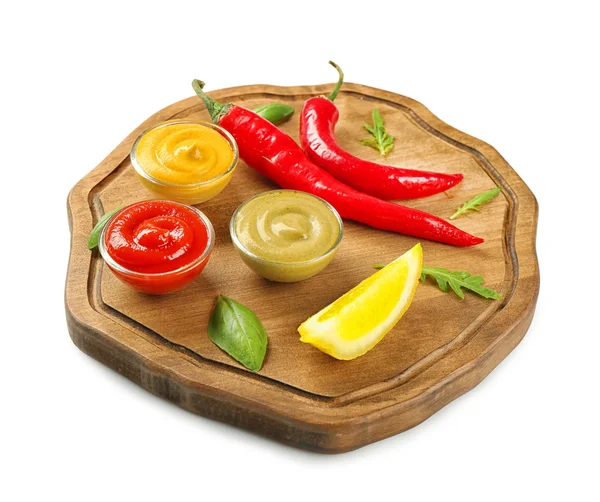 Placa de madera con diferentes salsas, chile y rodaja de limón sobre fondo blanco — Foto de Stock