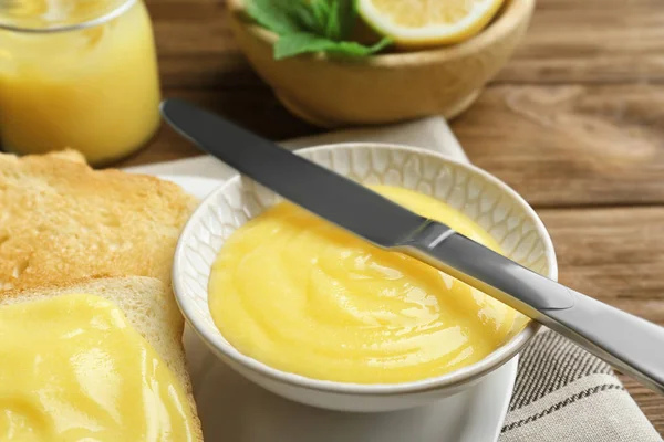 Delicious lemon curd and fresh toasts on wooden table, closeup — Stock Photo, Image