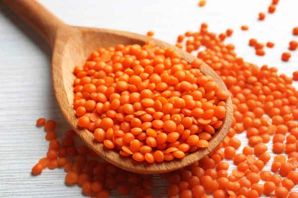 Red spoon of lentils on wooden background — Stock Photo, Image