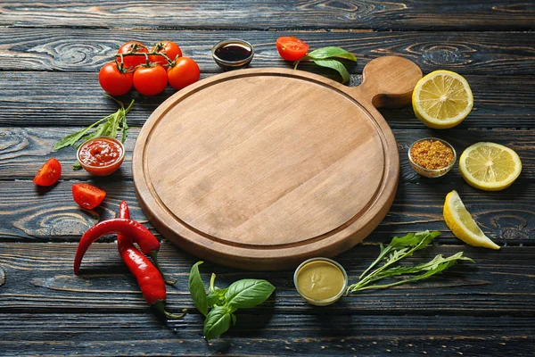 Деревянная доска, различные соусы и овощи на столе — стоковое фото