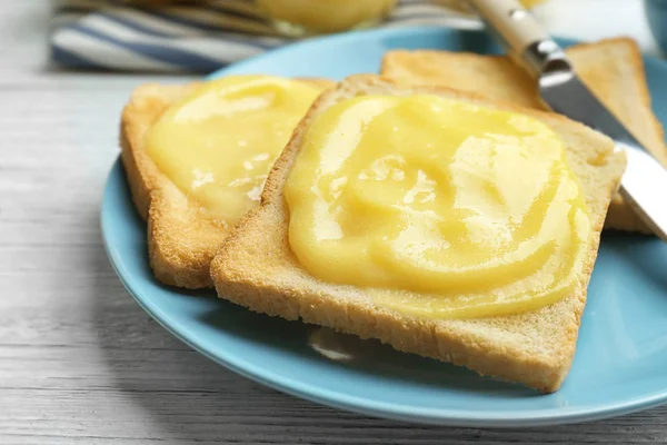 Piatto con pane tostato fresco e deliziosa cagliata di limone sul tavolo di legno, primo piano — Foto Stock