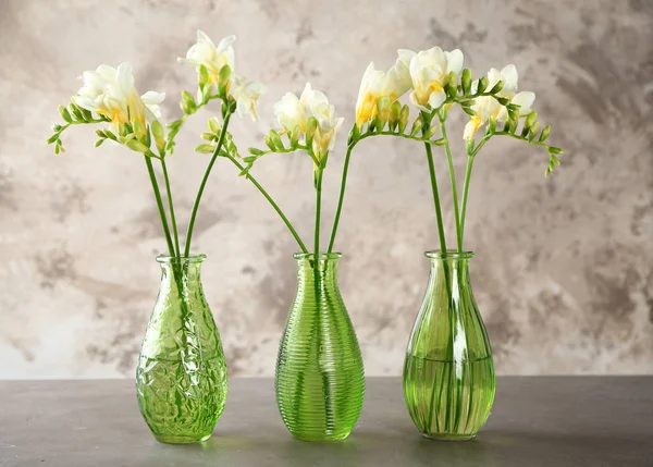 Three beautiful bouquets of fresh freesia in vases on table — Stock Photo, Image