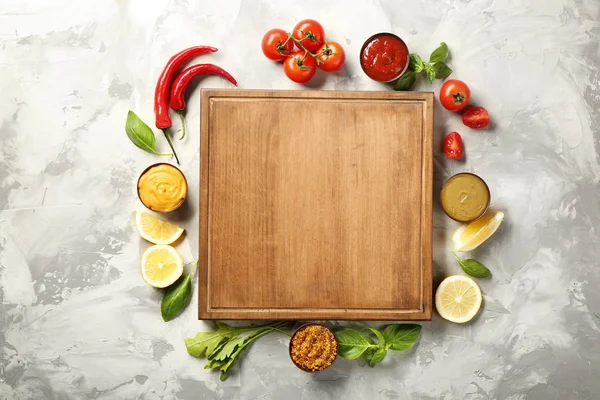 Assiette en bois, différentes sauces et légumes sur fond grunge — Photo