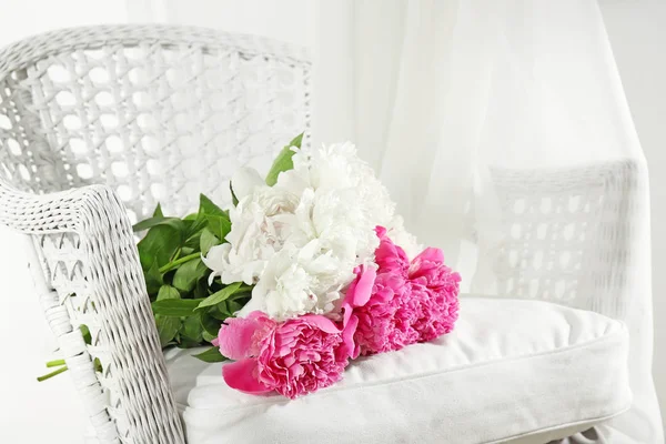 Buquê de belas flores de peônia na cadeira de vime branco — Fotografia de Stock