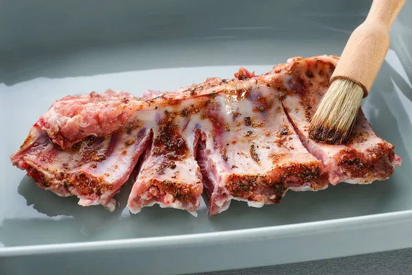 Baking tray with raw pork ribs and basting brush, closeup — Stock Photo, Image