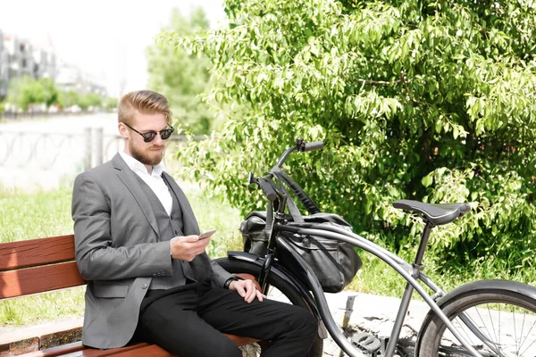 公園で自転車とベンチに座っている若い男 — ストック写真