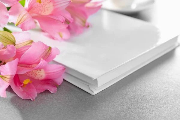 Libro con cubierta blanca en blanco y hermosas flores sobre fondo gris — Foto de Stock