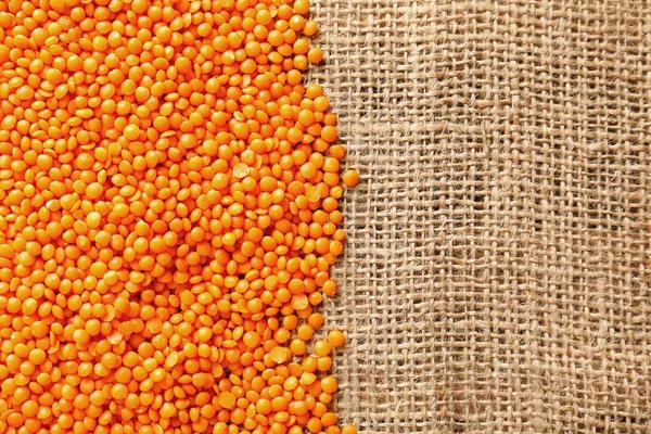 Red lentils on sackcloth background — Stock Photo, Image