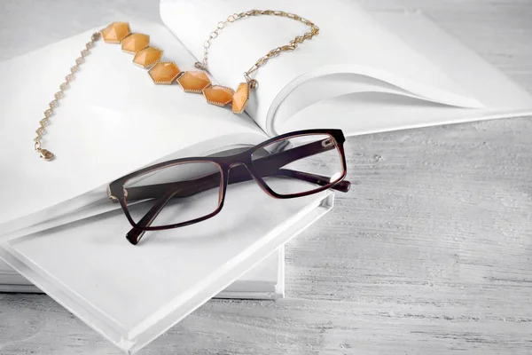 Schöne Komposition mit leeren Büchern, Halskette und Brille auf weißem Holzhintergrund — Stockfoto