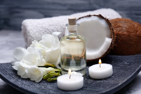 Composition with coconut oil in bottle for spa treatment on dark plate — Stock Photo, Image