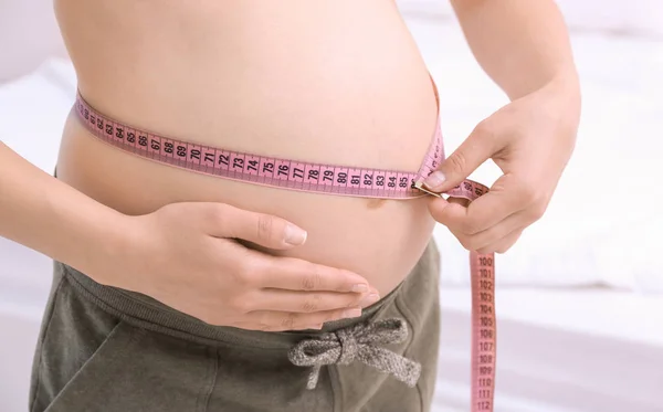 Hamilelik ağırlık kazanç kavramı. Hamile kadının karnı closeup ölçme — Stok fotoğraf