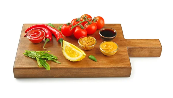 Dřevěná deska s různými omáčkami a zeleniny na bílém pozadí — Stock fotografie