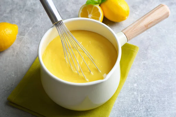 Sauce pan with delicious lemon curd and whisk on table — Stock Photo, Image