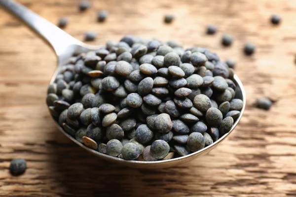 Grunge arka plan üzerinde siyah mercimek kaşıkla