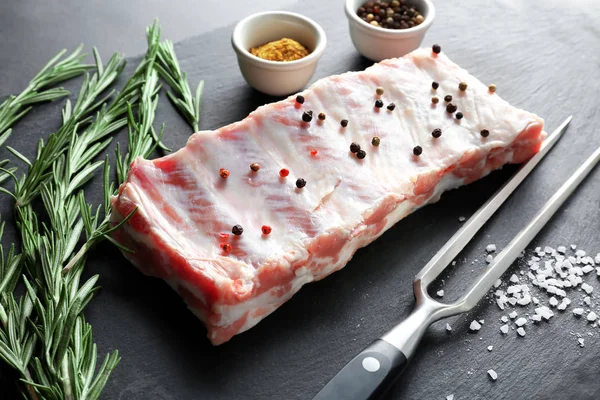 Costillas crudas con especias en plato de pizarra — Foto de Stock