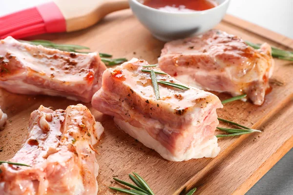 Costillas de cerdo y romero sobre tabla de madera, primer plano — Foto de Stock