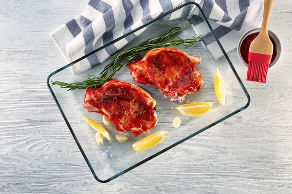 Schweinerippchen mit Tomatensauce und Zitronenscheiben im Glasbackblech auf dem Tisch — Stockfoto