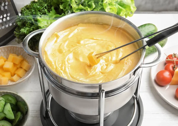 Pot with delicious cheese fondue on table, closeup
