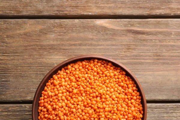 Tigela de lentilhas vermelhas no fundo de madeira — Fotografia de Stock