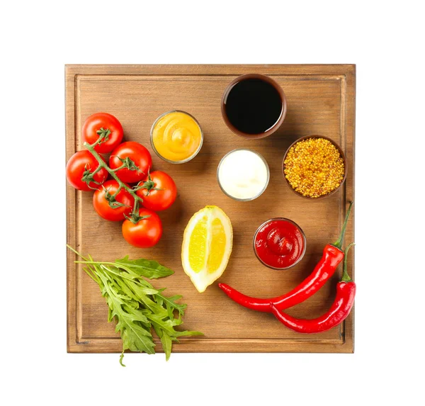 Holzteller mit verschiedenen Soßen und Gemüse auf weißem Hintergrund — Stockfoto