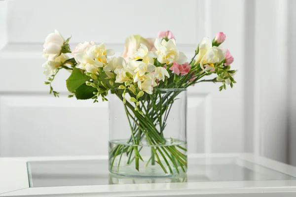 Beautiful bouquet of fresh freesia in vase on table Royalty Free Stock Images
