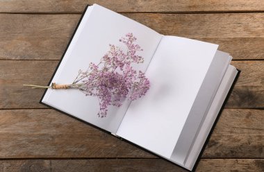Ahşap arka plan üzerinde boş sayfalar ve güzel çiçekler ile açık kitap