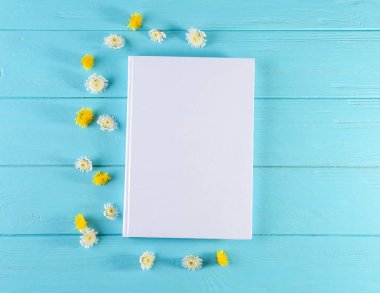 Boş beyaz kapak ve güzel çiçekler ile renk ahşap arka plan üzerinde kitap