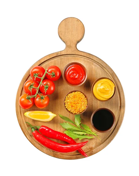 Tablero de madera con diferentes salsas y verduras sobre fondo blanco — Foto de Stock