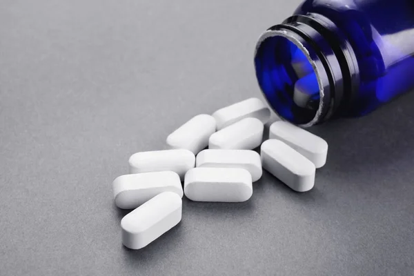 Concetto sanitario. Pillole e barattolo su sfondo grigio — Foto Stock