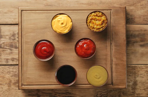 Tablero con diferentes salsas sobre fondo de madera —  Fotos de Stock