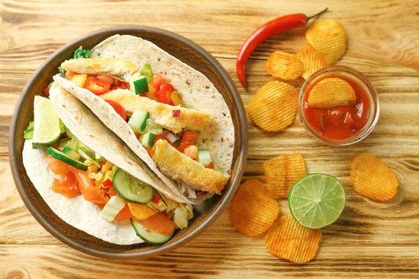 fish tacos on plate with sauce and chips