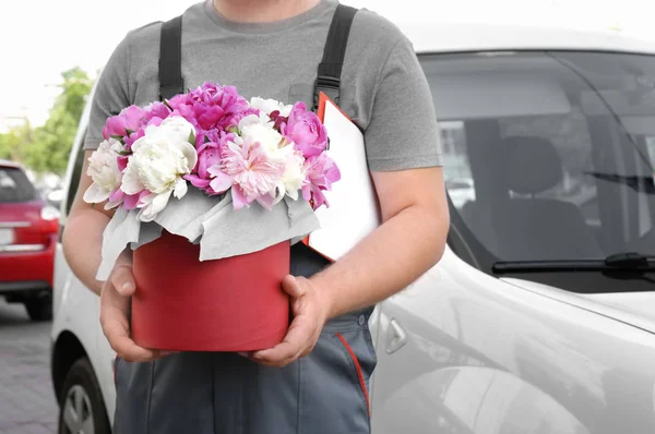 Levering man met mooie pioenroos bloemen — Stockfoto