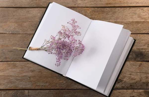 Ahşap arka plan üzerinde boş sayfalar ve güzel çiçekler ile açık kitap