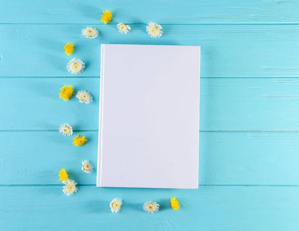 Libro con cubierta blanca en blanco y hermosas flores sobre fondo de madera de color —  Fotos de Stock