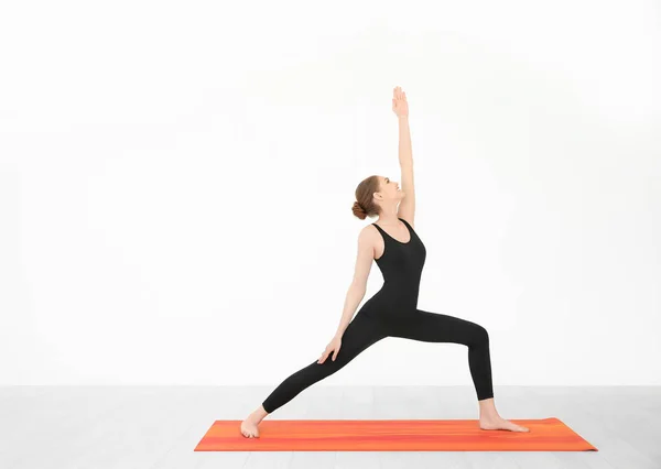 Joven hermosa mujer practicando yoga pose cerca de la pared blanca en el interior — Foto de Stock