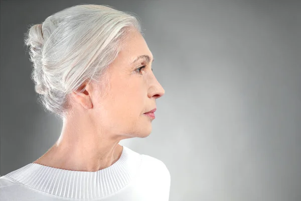 美丽优雅的老年妇女，在灰色的背景上 — 图库照片