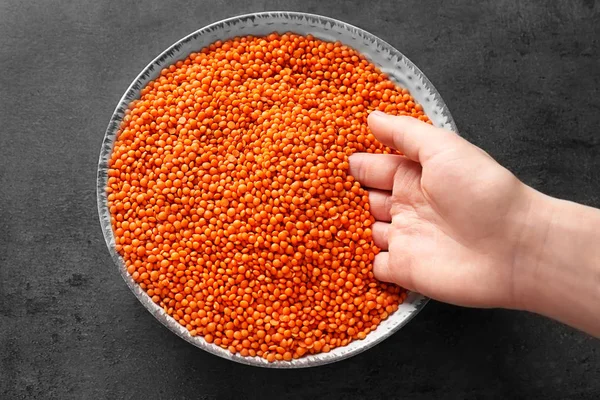 Female hand with red lentils in bowl on grey background — Stock Photo, Image