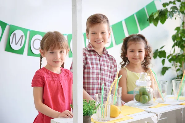 Niedliche kleine Kinder verkaufen Limonade an der Theke — Stockfoto