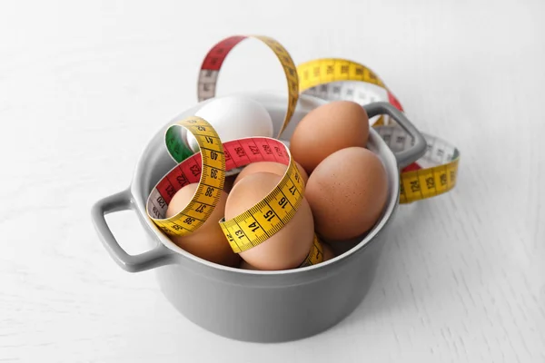 Bowl with eggs and measuring tape — Stock Photo, Image