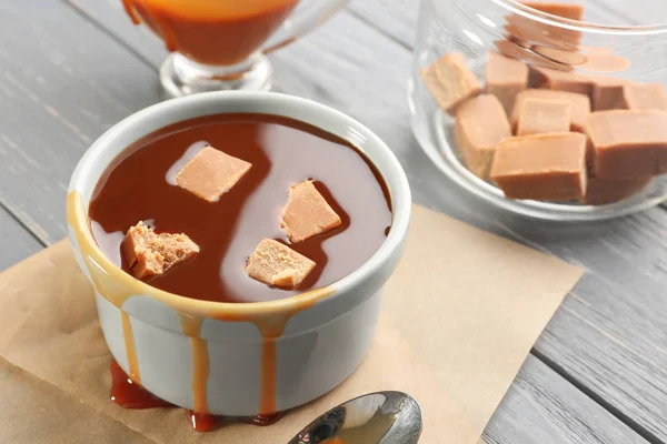 Bowl with caramel sauce and candies — Stock Photo, Image