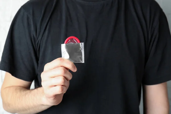 Hombre sosteniendo condón en la mano — Foto de Stock