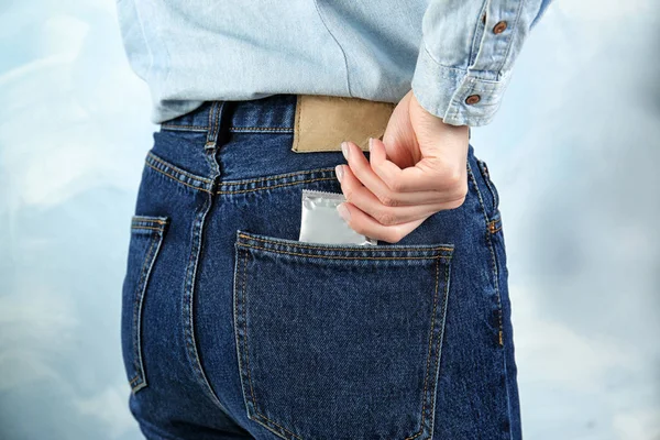 Женщина вытаскивает презерватив из джинсов — стоковое фото