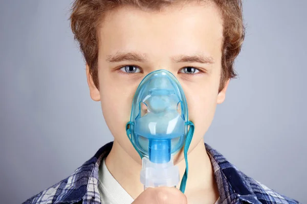 Menino usando nebulizador para asma e doenças respiratórias em fundo claro — Fotografia de Stock