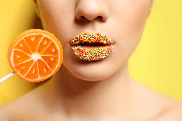 Beautiful young woman holding lollipop near lips — Stock Photo, Image