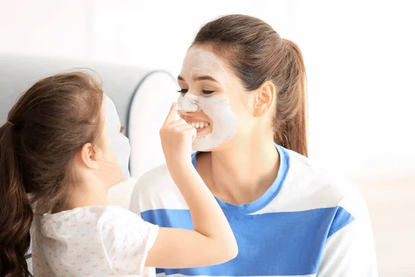 Junge Frau und ihre kleine Tochter mit Gesichtsmasken zu Hause — Stockfoto