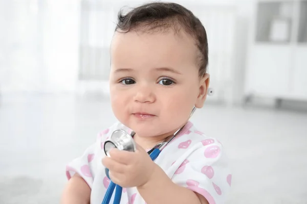 Piccolo bambino carino che gioca con lo stetoscopio a casa. Concetto sanitario — Foto Stock