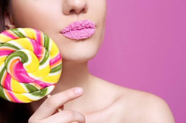 Dudaklar yakınındaki lolipop tutan güzel genç kadın 